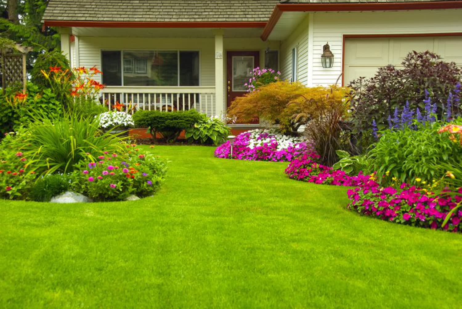 A home with lush planted beds and a green lawn